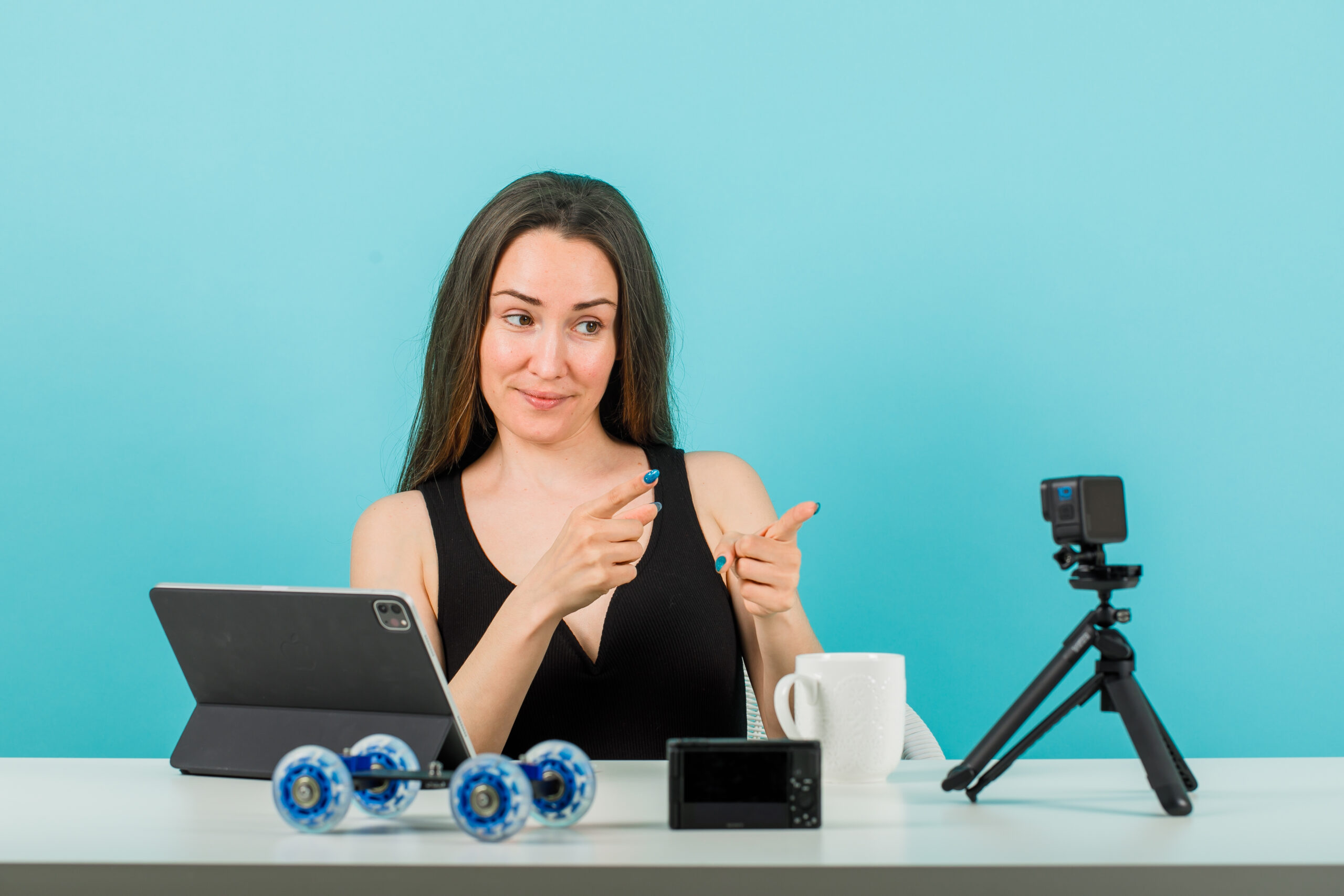 smiling blogger girl is posing camera by pointing camera with forefingers blue background